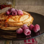 Fluffy pancakes with maple syrup and raspberries